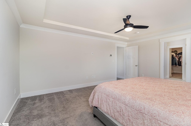 carpeted bedroom featuring baseboards, a raised ceiling, a ceiling fan, and ornamental molding