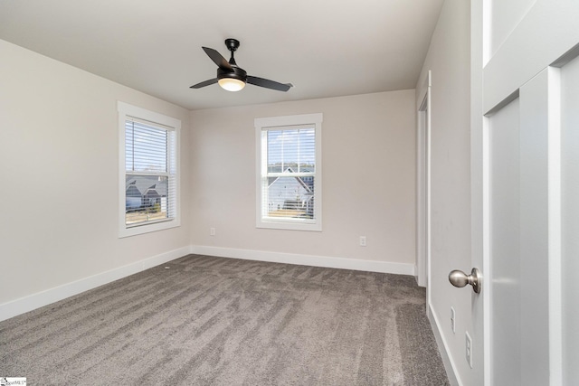 unfurnished bedroom featuring multiple windows, dark carpet, baseboards, and ceiling fan