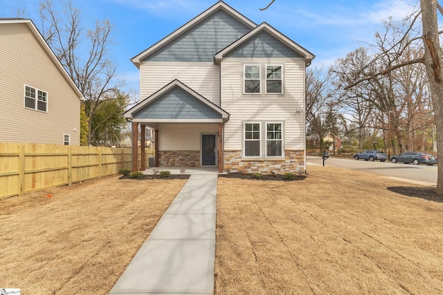 view of front of house featuring stone siding and fence