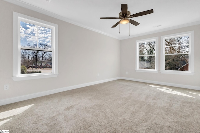 carpeted empty room featuring a ceiling fan, baseboards, and crown molding