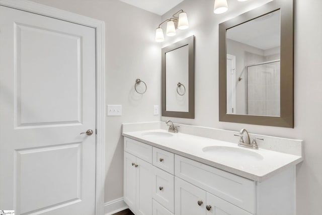 bathroom featuring double vanity, baseboards, walk in shower, and a sink