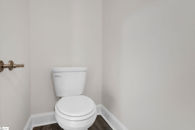 bathroom with toilet, baseboards, and wood finished floors