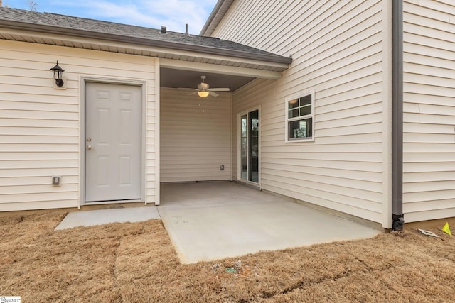 view of exterior entry with ceiling fan and a patio