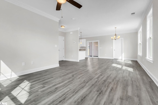 unfurnished living room with ceiling fan with notable chandelier, ornamental molding, wood finished floors, and baseboards