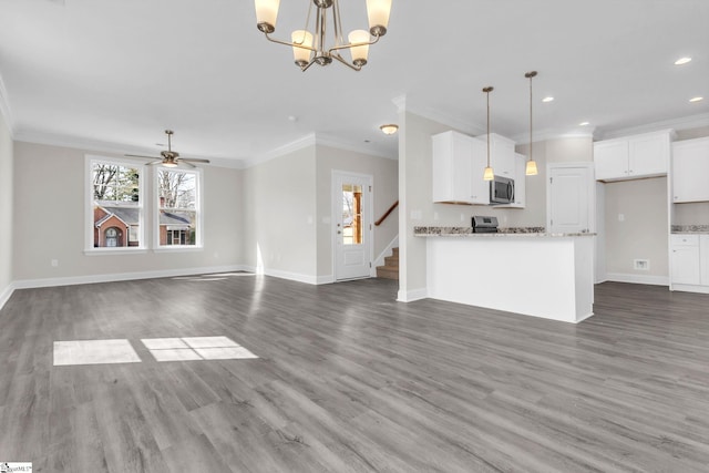 kitchen with hanging light fixtures, stainless steel microwave, white cabinets, and wood finished floors