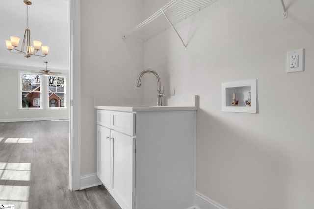 laundry area featuring washer hookup, wood finished floors, cabinet space, and baseboards