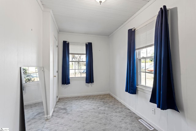 spare room featuring plenty of natural light, carpet, visible vents, and crown molding