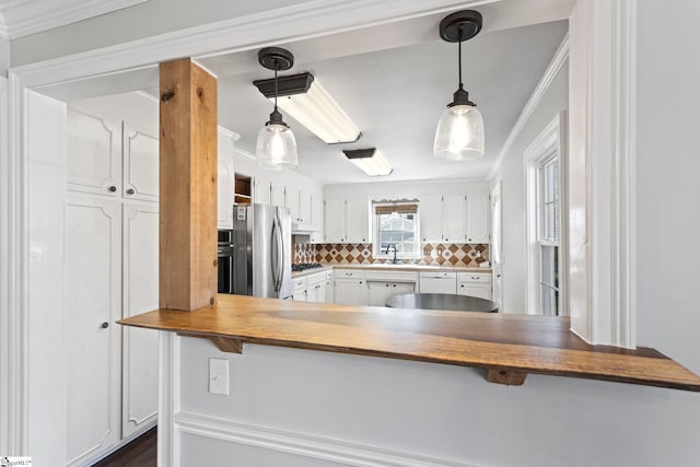 kitchen featuring tasteful backsplash, appliances with stainless steel finishes, a sink, and ornamental molding