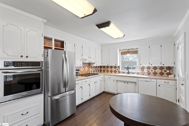 kitchen featuring crown molding, appliances with stainless steel finishes, dark wood-type flooring, white cabinetry, and a sink