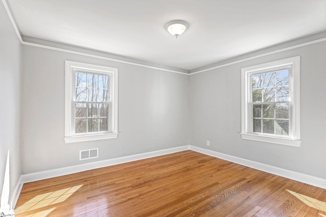 spare room with baseboards, visible vents, and hardwood / wood-style floors