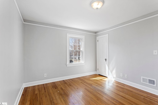 unfurnished room featuring ornamental molding, baseboards, visible vents, and hardwood / wood-style floors