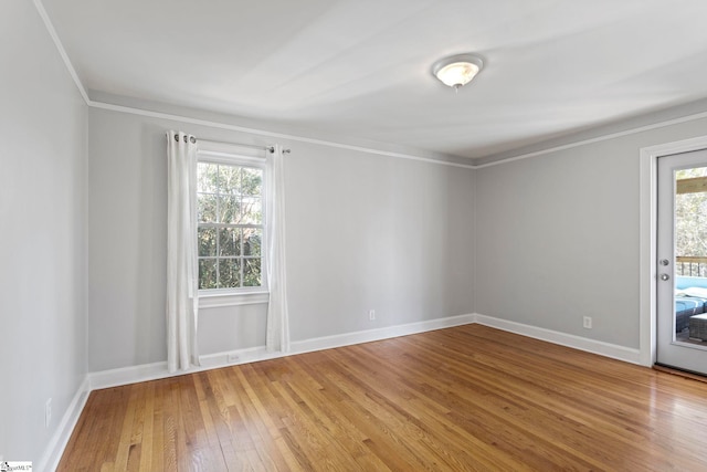 unfurnished room with a wealth of natural light, baseboards, crown molding, and hardwood / wood-style floors