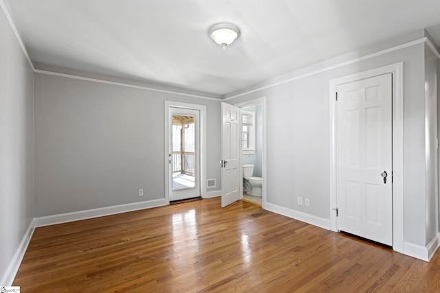 unfurnished bedroom featuring ornamental molding, baseboards, and wood finished floors