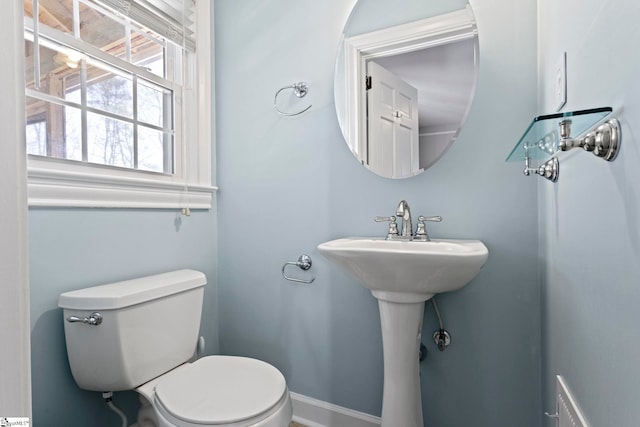 half bath with baseboards and toilet