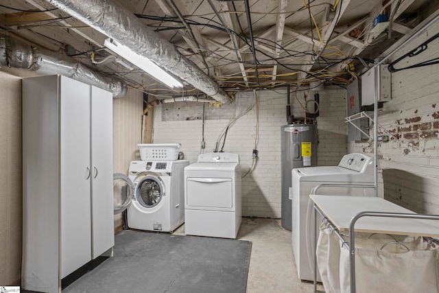 laundry room featuring laundry area, brick wall, separate washer and dryer, and electric water heater