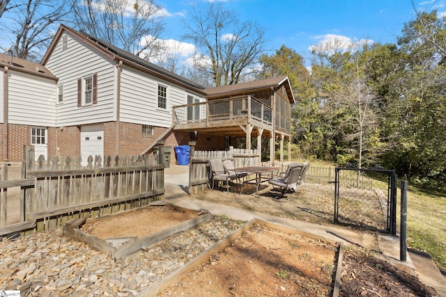 back of property with a garden, fence, a deck, and brick siding