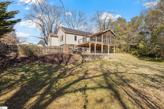 back of property with a deck, brick siding, fence, a sunroom, and a lawn