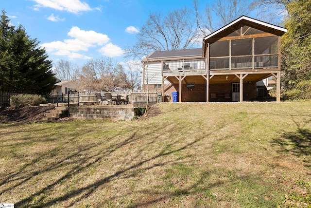 back of property featuring a yard, brick siding, a wooden deck, and a sunroom