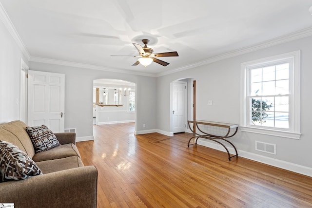 living room featuring light wood-type flooring, arched walkways, a wealth of natural light, and visible vents