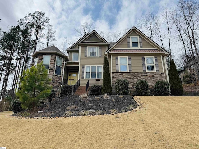 craftsman-style home featuring stone siding, a front yard, metal roof, and a standing seam roof