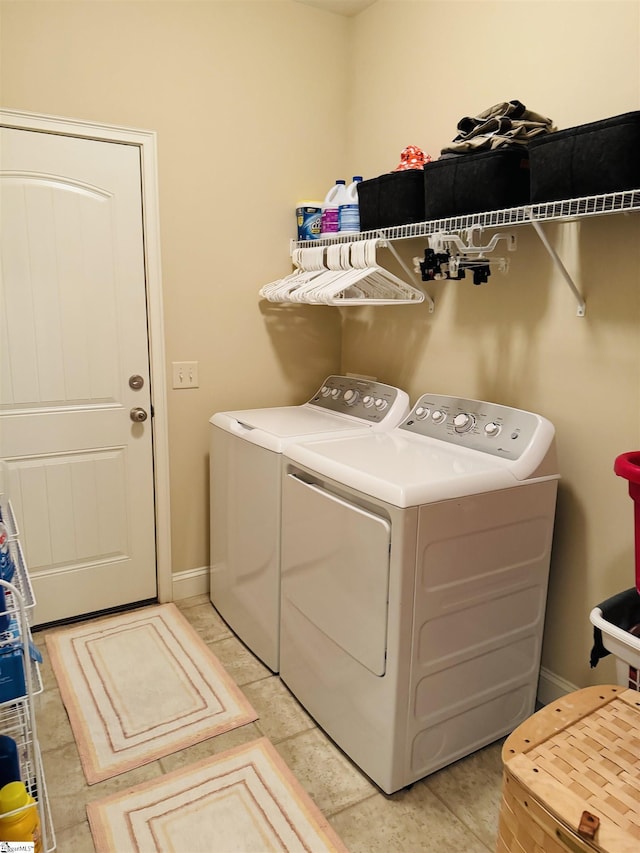 laundry room with laundry area, light tile patterned floors, baseboards, and washing machine and clothes dryer