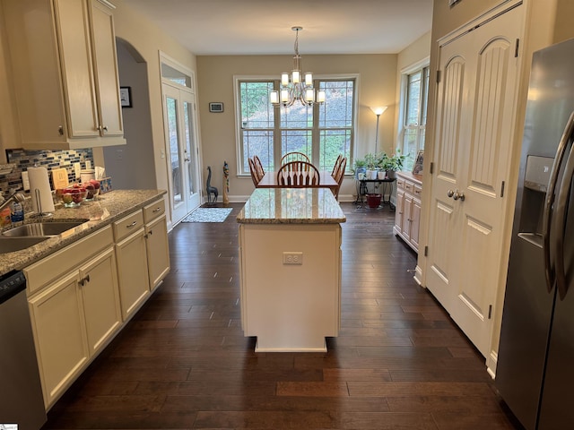 kitchen with stainless steel appliances, a sink, a center island, decorative backsplash, and dark wood-style floors