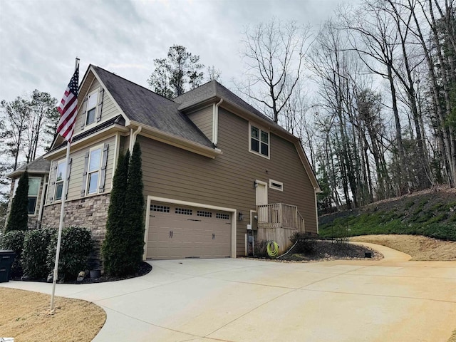 view of home's exterior featuring stone siding and concrete driveway