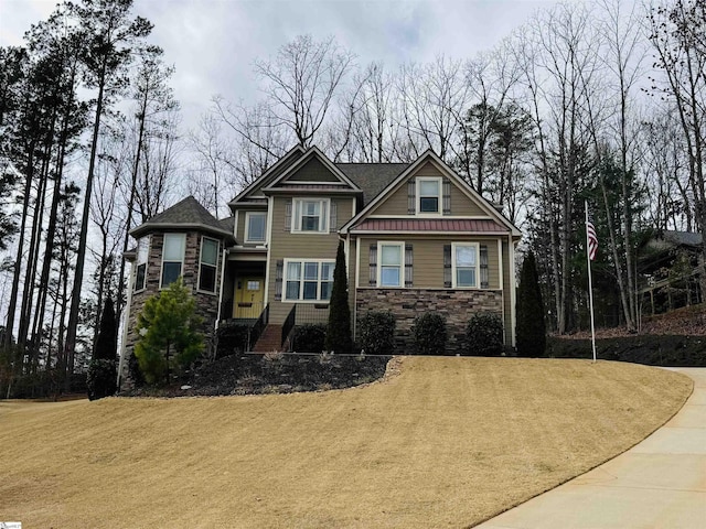 craftsman-style home with stone siding and a front yard