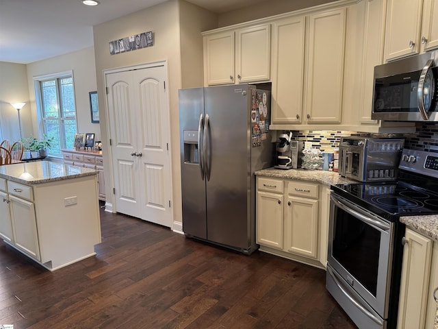 kitchen featuring appliances with stainless steel finishes, dark wood finished floors, light stone countertops, and decorative backsplash