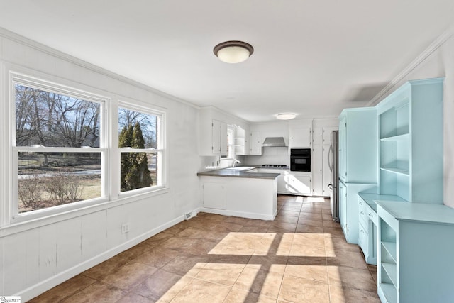 kitchen with a peninsula, black oven, wall chimney range hood, freestanding refrigerator, and open shelves