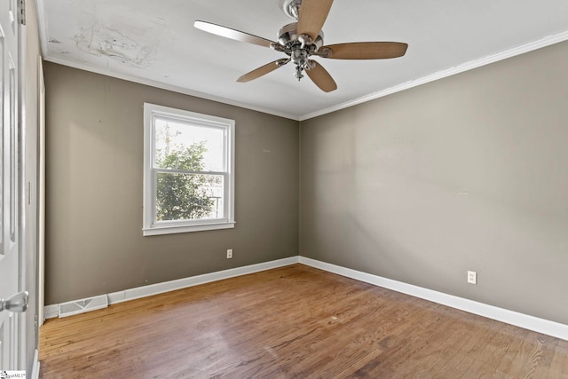 unfurnished room with attic access, visible vents, baseboards, wood finished floors, and crown molding