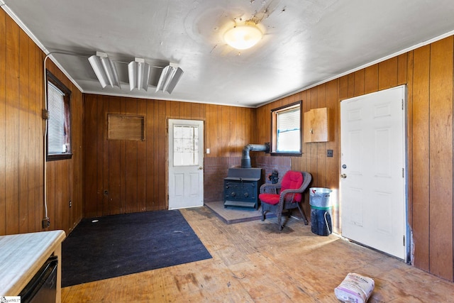 foyer entrance featuring light wood finished floors, wood walls, and a wood stove