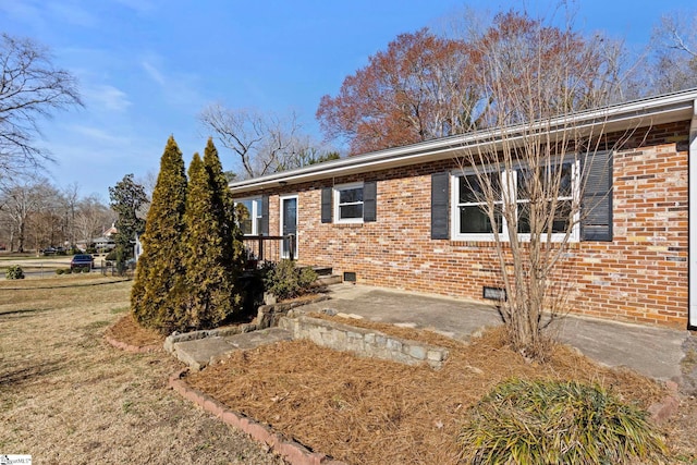 view of front facade featuring a front yard, crawl space, brick siding, and a patio