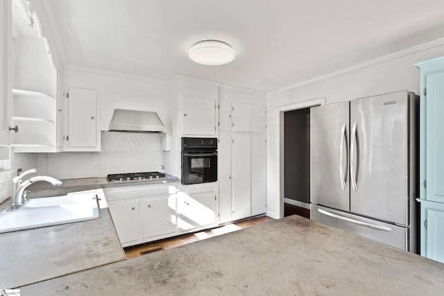 kitchen featuring stainless steel appliances, ornamental molding, white cabinetry, a sink, and wall chimney exhaust hood