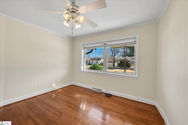 unfurnished room featuring visible vents, ornamental molding, a ceiling fan, wood finished floors, and baseboards