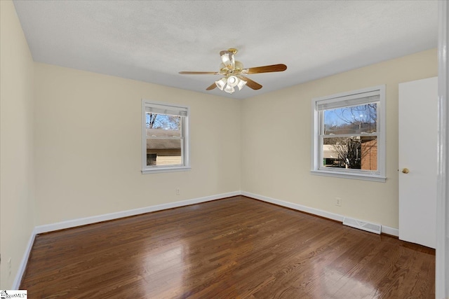 spare room with baseboards, visible vents, dark wood-style floors, ceiling fan, and a textured ceiling