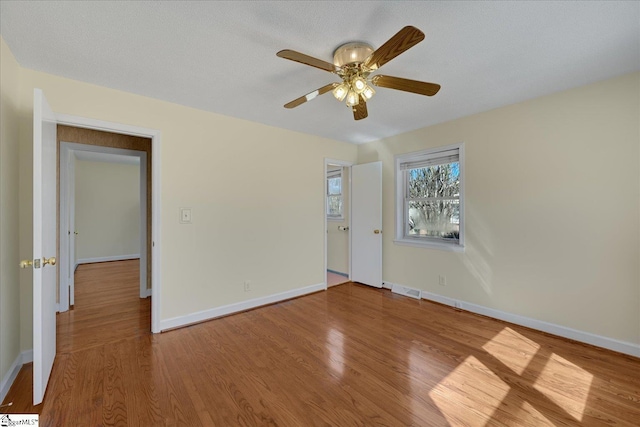 empty room featuring visible vents, baseboards, ceiling fan, and wood finished floors