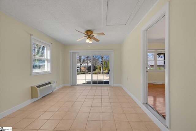 doorway to outside with a healthy amount of sunlight, light tile patterned flooring, a textured ceiling, and a wall mounted AC