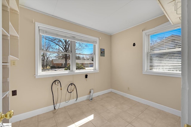 laundry area with baseboards, ornamental molding, and light tile patterned flooring