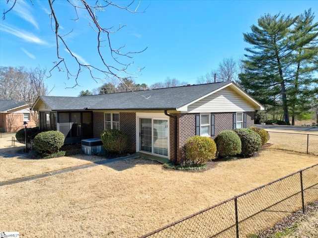 ranch-style home featuring a shingled roof, fence, and brick siding