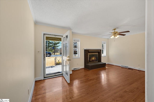 unfurnished living room with visible vents, a fireplace, a textured ceiling, and wood finished floors