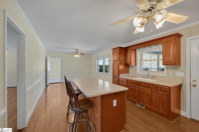 kitchen featuring light wood-style floors, a kitchen island, light countertops, and a sink