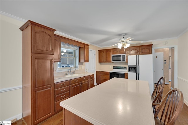 kitchen with white appliances, brown cabinets, light countertops, crown molding, and a sink