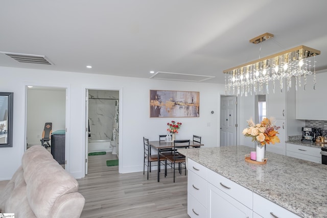 kitchen featuring recessed lighting, visible vents, light wood-style flooring, white cabinetry, and light stone countertops