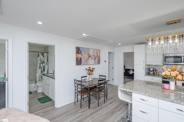 interior space featuring white cabinets, stainless steel microwave, a sink, and light wood-style flooring