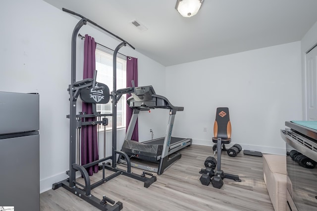 exercise room with baseboards, visible vents, and light wood-style floors