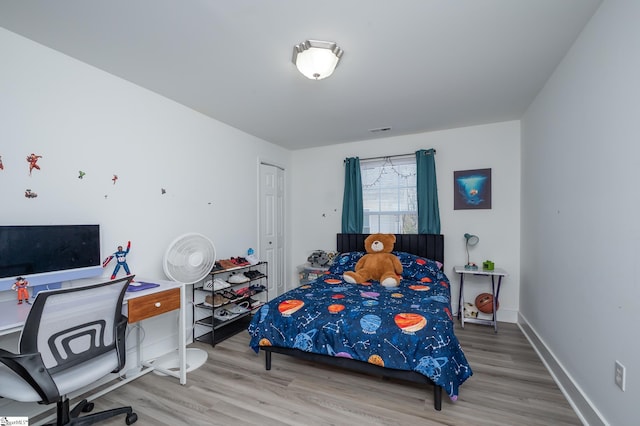 bedroom featuring a closet, visible vents, baseboards, and wood finished floors