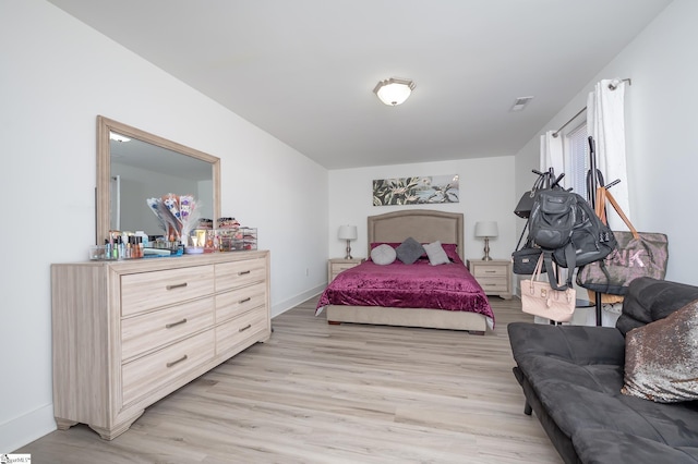 bedroom with light wood-type flooring, visible vents, and baseboards