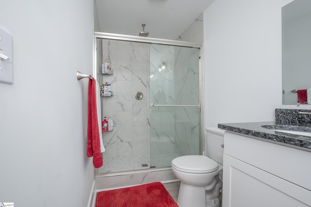 bathroom featuring toilet, a marble finish shower, and vanity