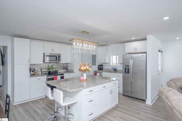 kitchen featuring a center island, stainless steel appliances, light wood-type flooring, white cabinetry, and a sink